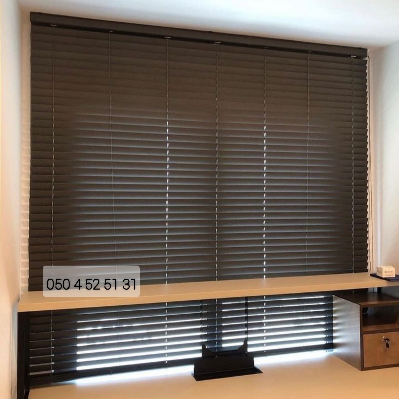 Dark wooden venetian blinds fitted across a wide office window