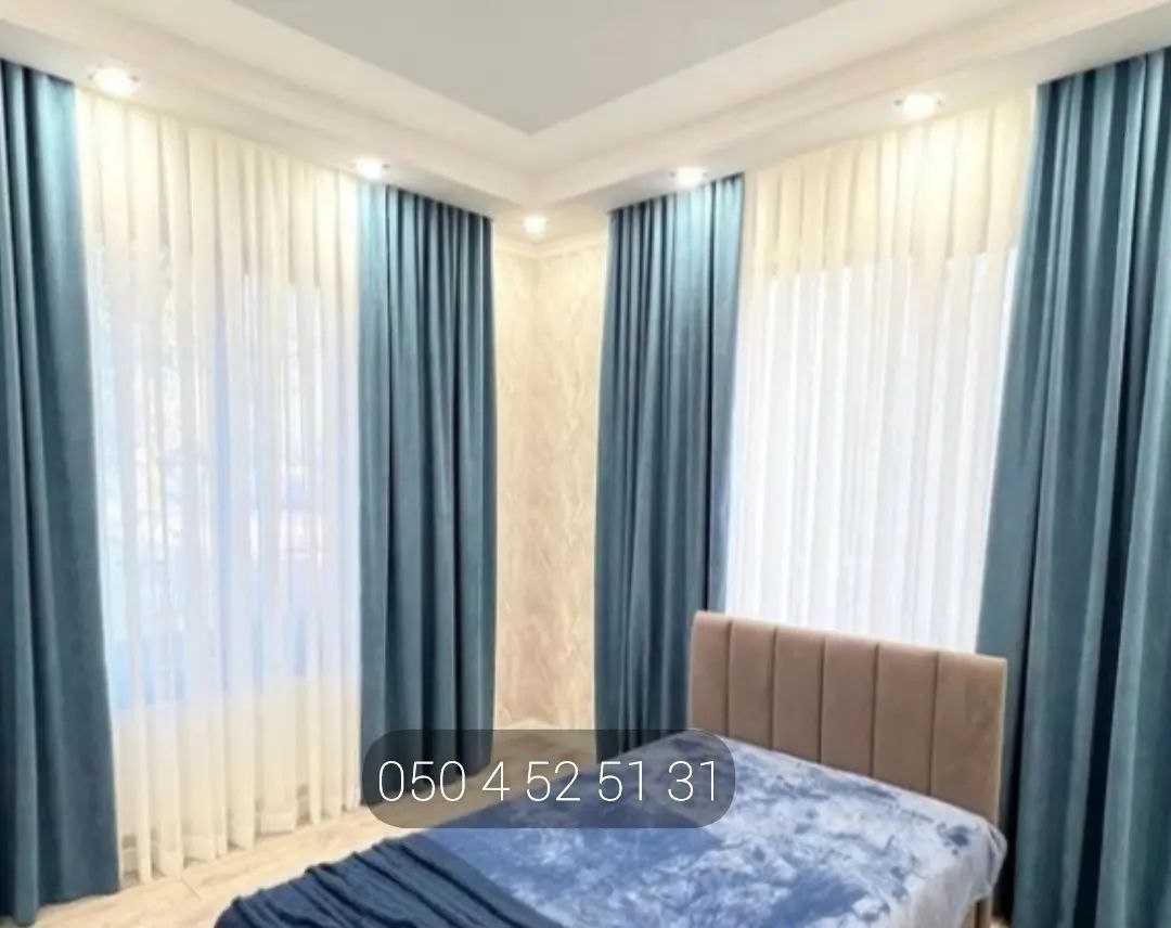 Teal curtains and white sheers wrapping a corner bedroom